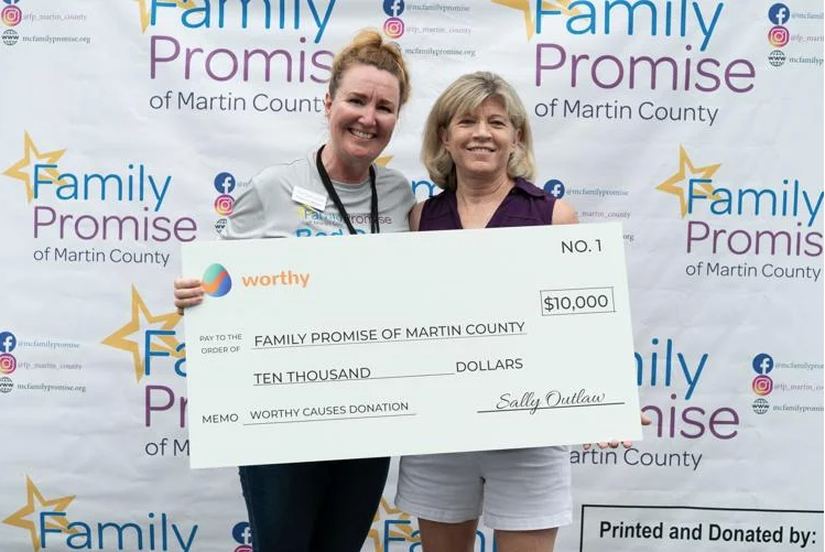 Madeleine Bozone-Greenwood, executive director of Family Promise of Martin County, accepting a $10,000 check from Sally Outlaw, chair of Worthy Property Bonds.